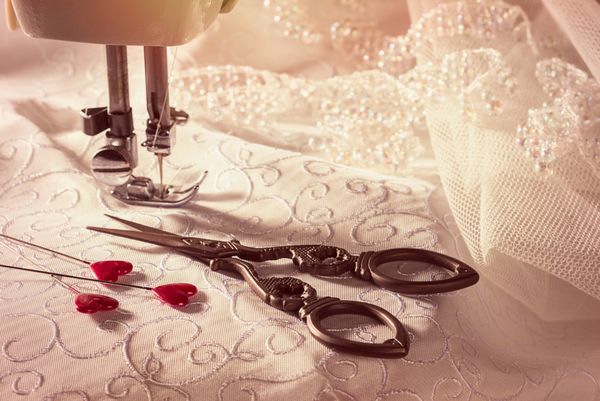 دوخت قیچی با پین های قلب شکل در لباس عروسی و توری تمرکز بر روی قیچی و پین