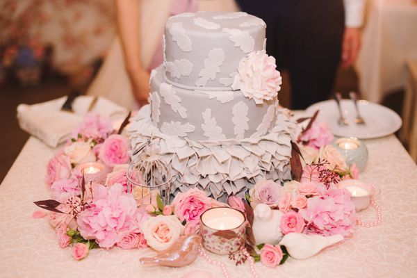 کیک عروسی بر روی میز تزئینی با شمع و گل دسر شیرین در پذیرش طراحی رویداد