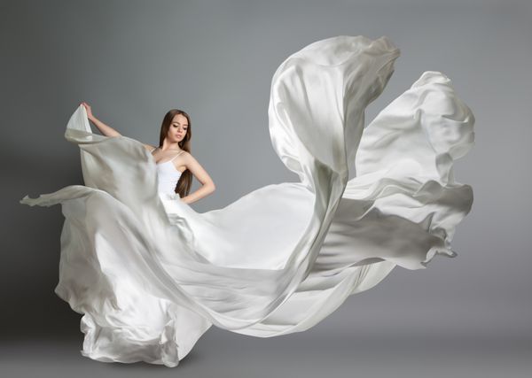 دختر جوان زیبا دختر در پرواز لباس سفید یک پارچه سفید در هوا پرواز می کند لباس سفید سفید