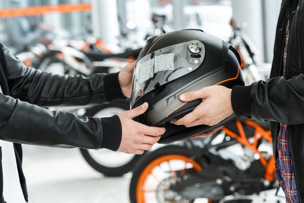 تضمین ایمنی شات از یک مدیر سالن موتور سیکلت عبور یک کلاه ایمنی به مشتری خود را در سالن موتورسیکلت