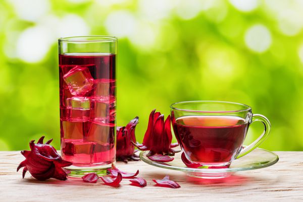 جام چای هیبیزیک کرکست گلابی قرمز Agua de flor de جامائیکا و همان نوشیدنی سرد با یخ در شیشه در زمینه طبیعت نوشیدنی های ساخته شده از گل های زردآلو دانه ها گل های گل رز