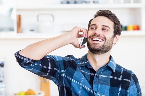 یک مرد در حال صحبت کردن با تلفن و لبخند زدن در محل کار است