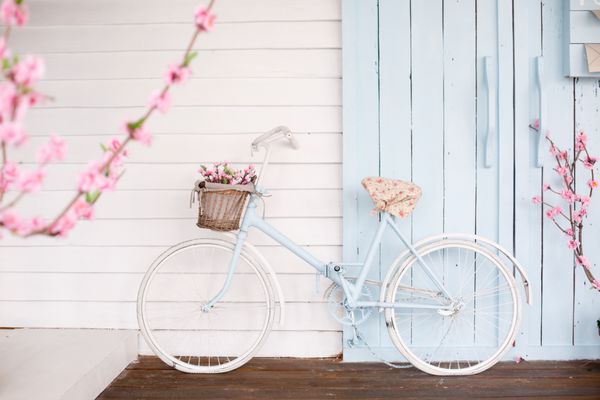 دوچرخه سفید با سبد گل زیبا در زمینه پس زمینه در فصل بهار