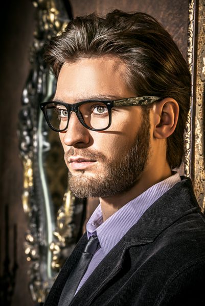 Portrait of a handsome young man standing by a golden vintage wallpaper Luxury Men