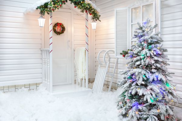 بیرونی زمستانی یک خانه ای با دکوراسیون کریسمس در سبک آمریکایی حیاط تحت پوشش برف با سورتمه های حیاط درخت و چوبی