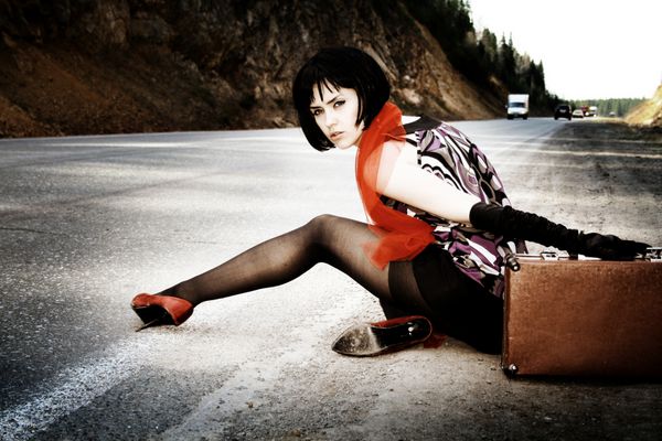 دختر مد با چمدان ماشین را در جاده متوقف می کند