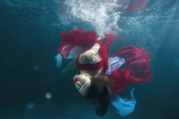 در استخر زیر آب او در یک لباس قرمز است