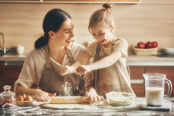 خانواده دوست داشتنی با هم در حال تهیه نانوایی هستند دختر مادر و دختر کوکی پخت و پز و سرگرم کننده در آشپزخانه است غذای خانگی و کمکی کم