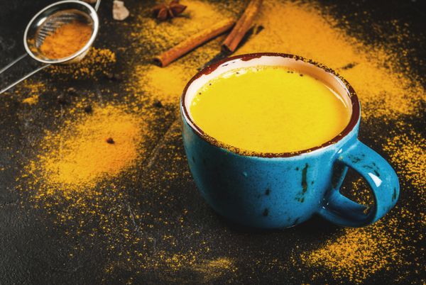شیرین زردچوبه نوشیدنی سنتی هندوانه دارچین فلفل و زردچوبه شیر طلایی است روی میز بتن با ادویه جات بر روی زمینه در یک فنجان بزرگ فضای کپی رنگی شده است