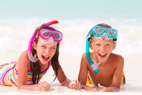پسر خوش تیپ و دختر با snorkels در ساحل شنی دریا در پس زمینه