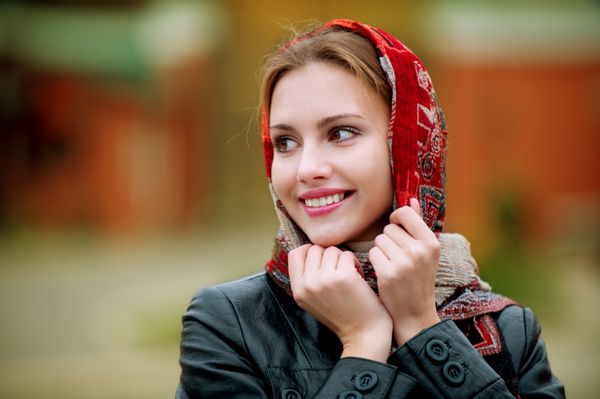 زن جوان لبخند زدن در روسری قرمز در راه رفتن