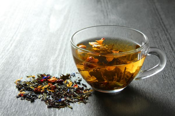 چای گیاهی خوشمزه را در یک زمینه سیاه و سفید چوبی می خورید