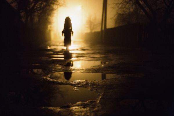 مرد تنهایی شهر در شب در مه غلیظ دود سیاهی در یک خیابان تاریک روشنایی مخلوط زیبا از ویندوز شبح مردم و درختان ستون در جاده