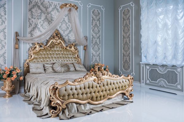 اتاق خواب لوکس در رنگ های روشن با جزئیات طلایی مبلمان بزرگ تخت سلطنتی دوگانه راحت در داخلی کلاسیک زیبا