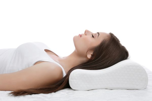 زن جوان خوابیدن در رختخواب با بالش ارتوپدی در مقابل زمینه سفید مفهوم منظر سالم