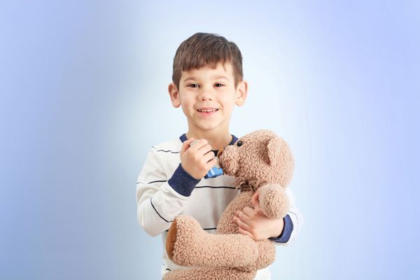 پسر کوچک ناز نگه داشتن استنشاق و اسباب بازی بر روی زمینه رنگی مفهوم آلرژی