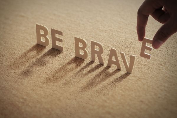 BE BRAVE wood word on compressed or corkboard with human