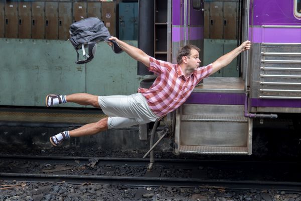 مرد با کوله پشتی پرواز می کند در قطار حرکت می کند گردشگری برگزاری قطار در حال حرکت از ایستگاه راه آهن مسافر خنده دار قطار را حرکت می دهد سفر به آخرین لحظه