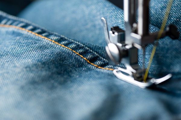 دوخت شلوار جین را با ماشین دوخت مفهوم صنعتی پوشاک