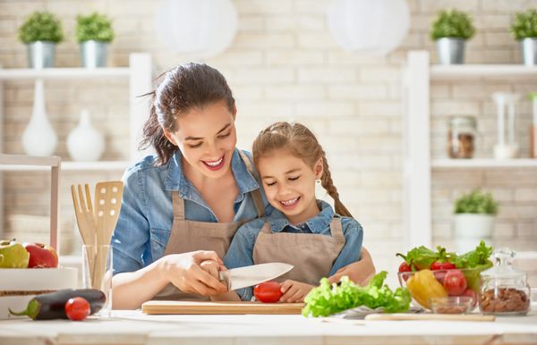 غذای سالم در خانه خانواده شاد در آشپزخانه مادر و فرزند دختر سبزیجات و میوه را تهیه می کنند