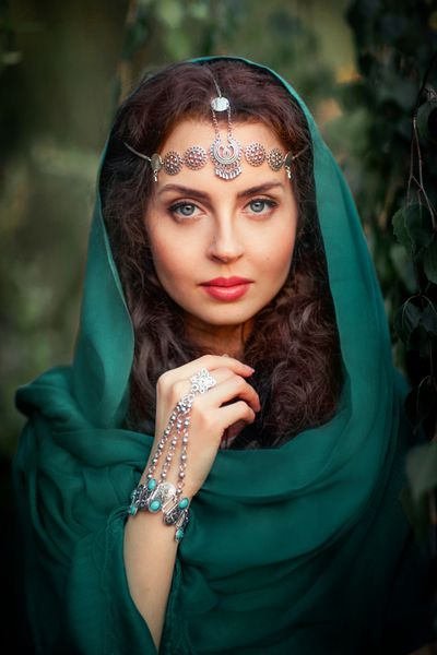 دختر زیبا در روسری و لوازم جانبی هند ایستاده در زمینه سبز و رویای زن زیبا زن به دوربین نگاه کرد
