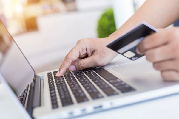 بستن زن دست نگه داشتن کارت اعتباری در مقابل لپ تاپ روی میز مفهوم خرید آسان آنلاین