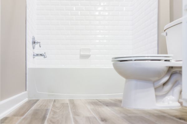 حمام توالت تمیز با دقت مدرن با کاشی های دوش و طبقه های چوب سخت از سطح زمین