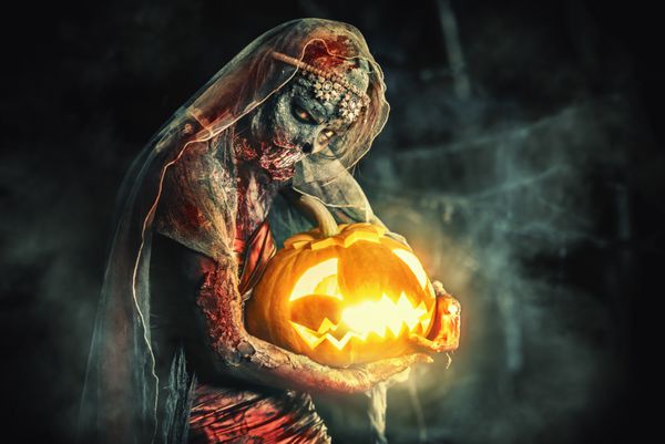 هالووین عروس ترسناک زامبی در یک گورستان شب یک فانوس کدو تنبل دارد