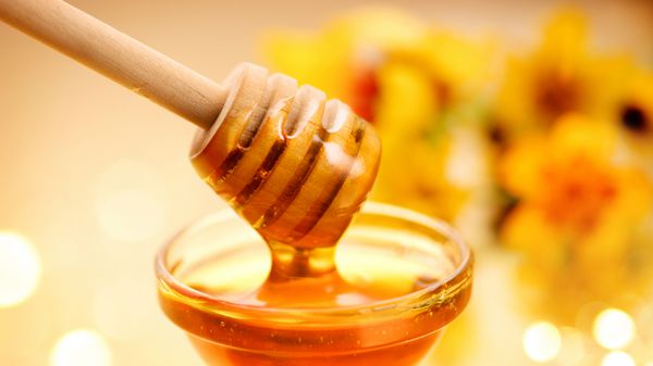 عسل از آب پرتقال عسل بر روی پس زمینه زرد است عسل ضخیم از قاشق عسل چوبی مفهوم غذایی سالم رژیم غذایی رژیم غذایی