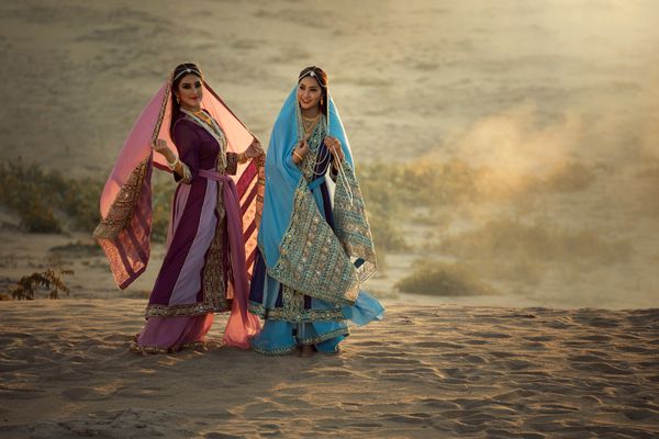 دو زن خوش تیپ ایرانی و یا لباس های سنتی عربی ایستاده توسط شن و ماسه