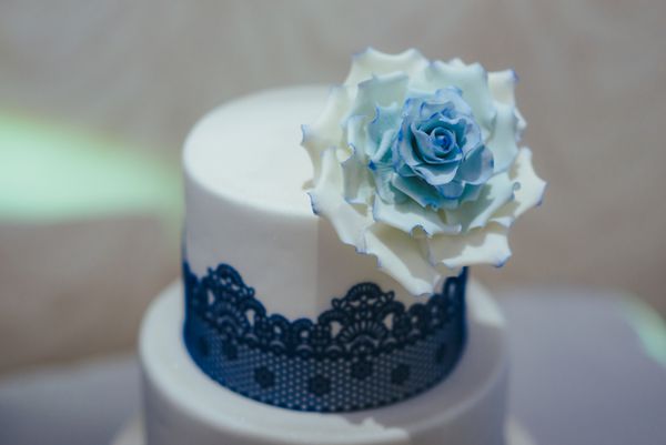 کیک عروسی آبی با گل های سفید تزئین شده است نزدیک از کیک عروسی آبی و سفید در پذیرش