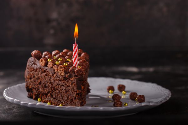 قطعه کیک شکلاتی با شمع در یک زمینه تاریک backgroundselectctive تمرکز