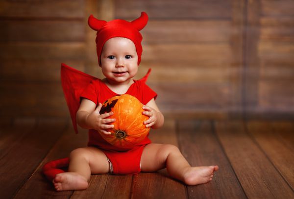 کودک خنده دار در لباس هالووین شیطان با کدو تنبل