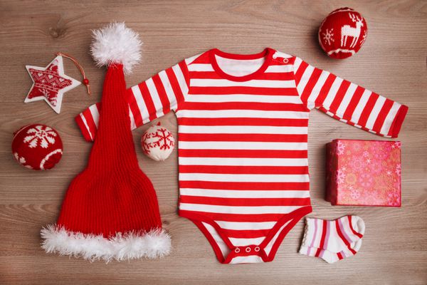 کریسمس لباس نوزاد با جواهرات کریسمس در پس زمینه چوبی بابا نوئل عزیزم لباس لباس کریسمس کودک مجموعه