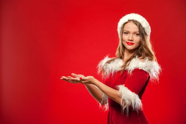 کریسمس X-mas زمستان مفهوم شادی زن لبخند زدن در کلاه اسپانیایی سانتا با جعبه هدیه دستان خود را در مقابل او ارائه پس زمینه قرمز بیش از قرمز است