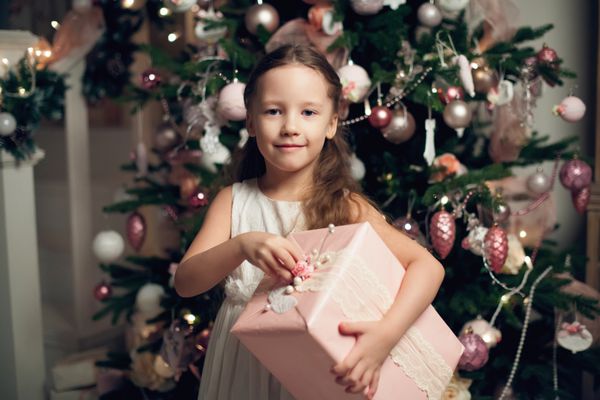 دختر در لباس ایستاده درخت درخت کریسمس و هدایای نگهداری