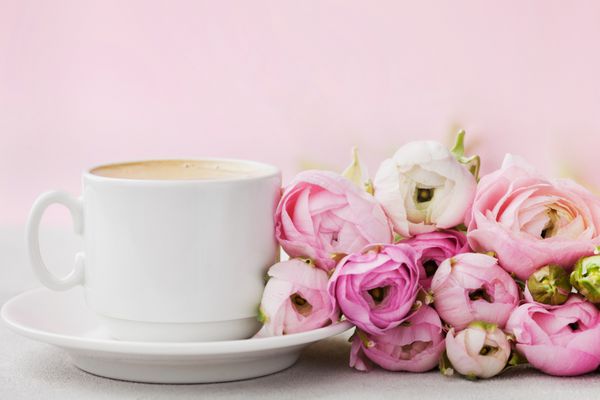 گل های زیبا Ranunculus و فنجان قهوه در میز خاکستری خاکستری رنگ پاستل کارت تبریک برای روز ولنتاین یا روز زنان صبحانه فضای خالی برای متن