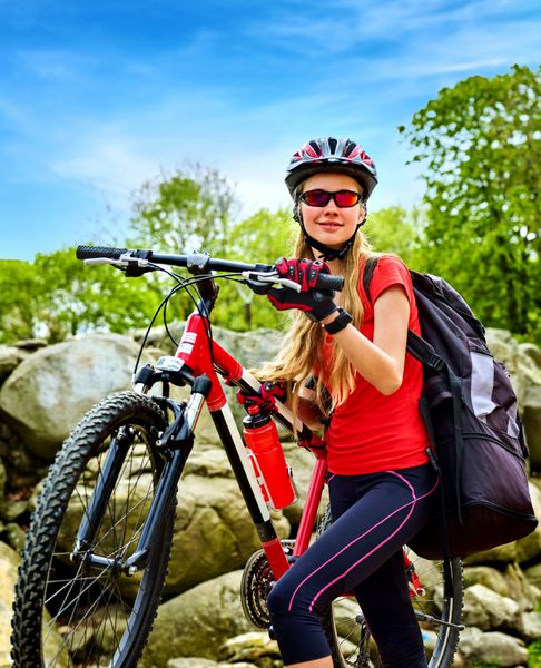 زن در کوه دوچرخه سواری دختر در پارک تابستانی مسافرت می کند صبح زود با آسمان آبی و ابرها دوچرخه سواری با کوله پشتی سفر ورزشی برای سلامتی خوب است