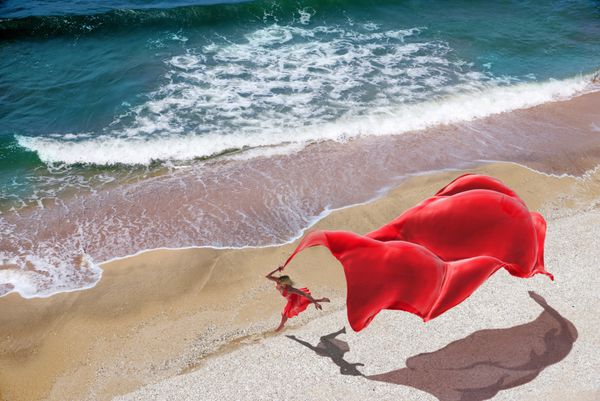 زن با بافت قرمز در ساحل