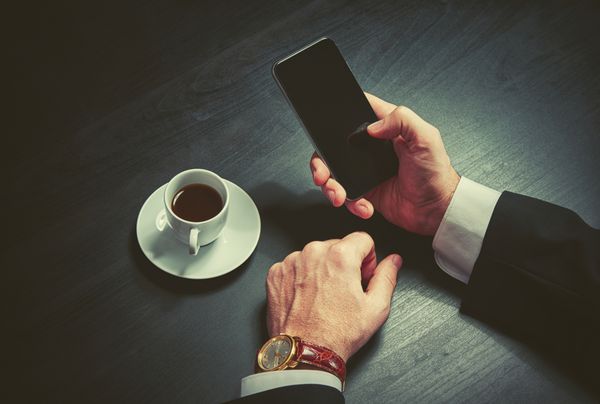 تلفن و فنجان قهوه در دست بازرگان