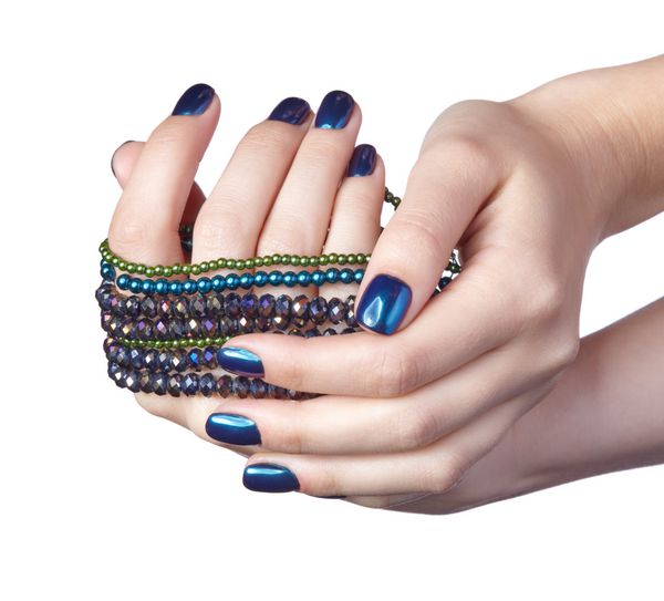زن با دانه جواهرات صحنه و لباس انگشتان زن با مانیکور ناخن براق آبی دختران با جواهرات جدا شده بر روی زمینه سفید دست