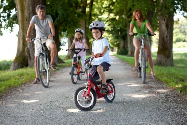 پسر 4 ساله در کنار دوچرخه سواری در کنار خانواده اش نشسته است