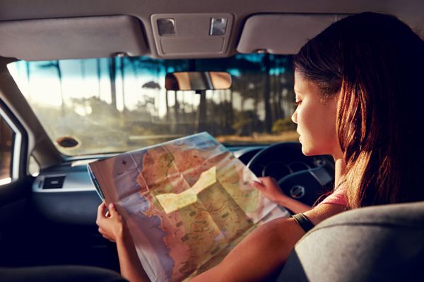 زن در تعطیلات به نقشه برای جهت در هنگام رانندگی در ماشین نگاه می کند