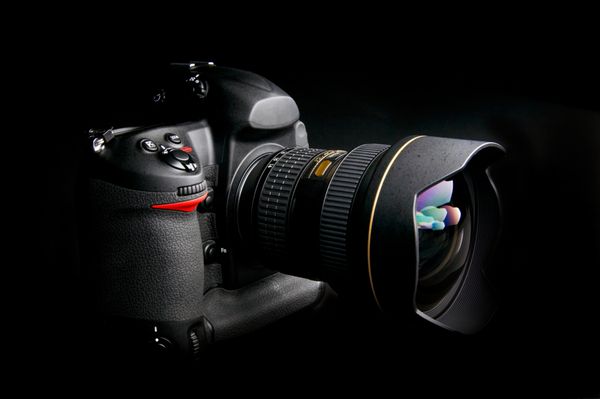 دوربین حرفه ای دیجیتال با لنز زوم در پس زمینه سیاه و سفید