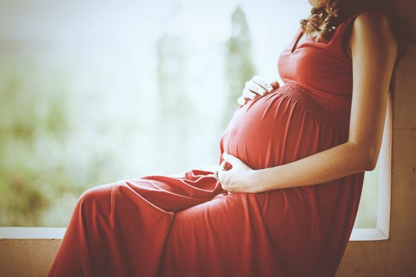 تصویر زن باردار لمس شکم خود را با دست
