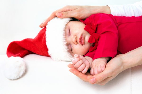 کودک ناز در کلاه سانتا خوابیدن در دست مادر