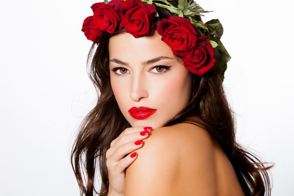 پرتره زیبا از یک زن جوان با یک گلدان گل رز قرمز در سر او استودیو سفید