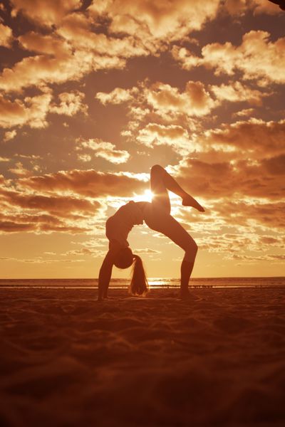 جوان زیبایی زن و شوهر silhouette عمل یوگا در ساحل در غروب آفتاب یوگا در طلوع آفتاب