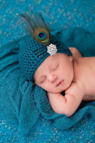 یک پرتره از یک دختر 12 روزه در خواب دختر نوزاد با پوشیدن یک کلاه بافتنی کت و شلوار زیبا با دکمه rhinestone و پرکته طاووس