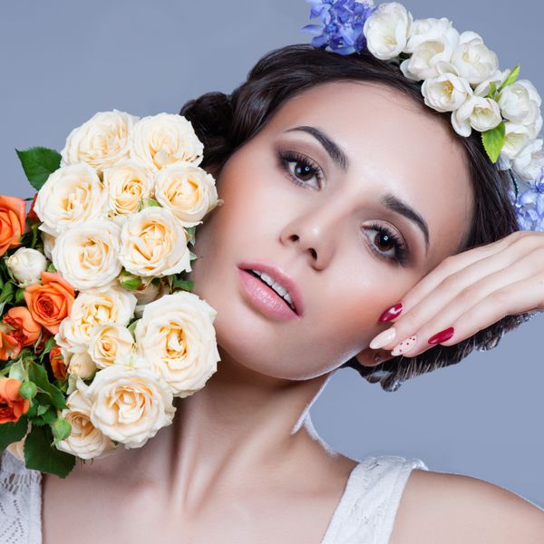زن جوان زیبا با گل های دلپذیر در موهایشان